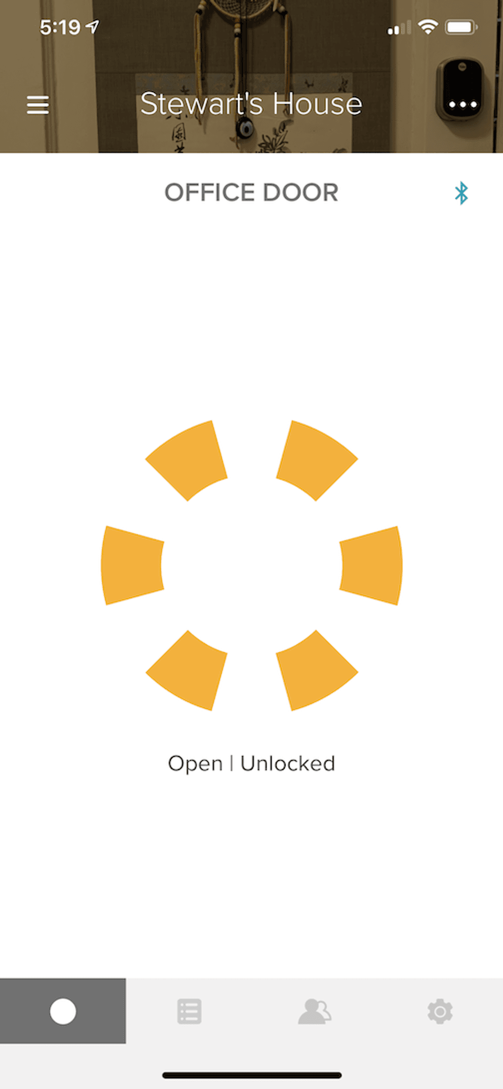 A photo of the app showing the Yale Assure Lock SL status as unlocked with a yellow pinwheel