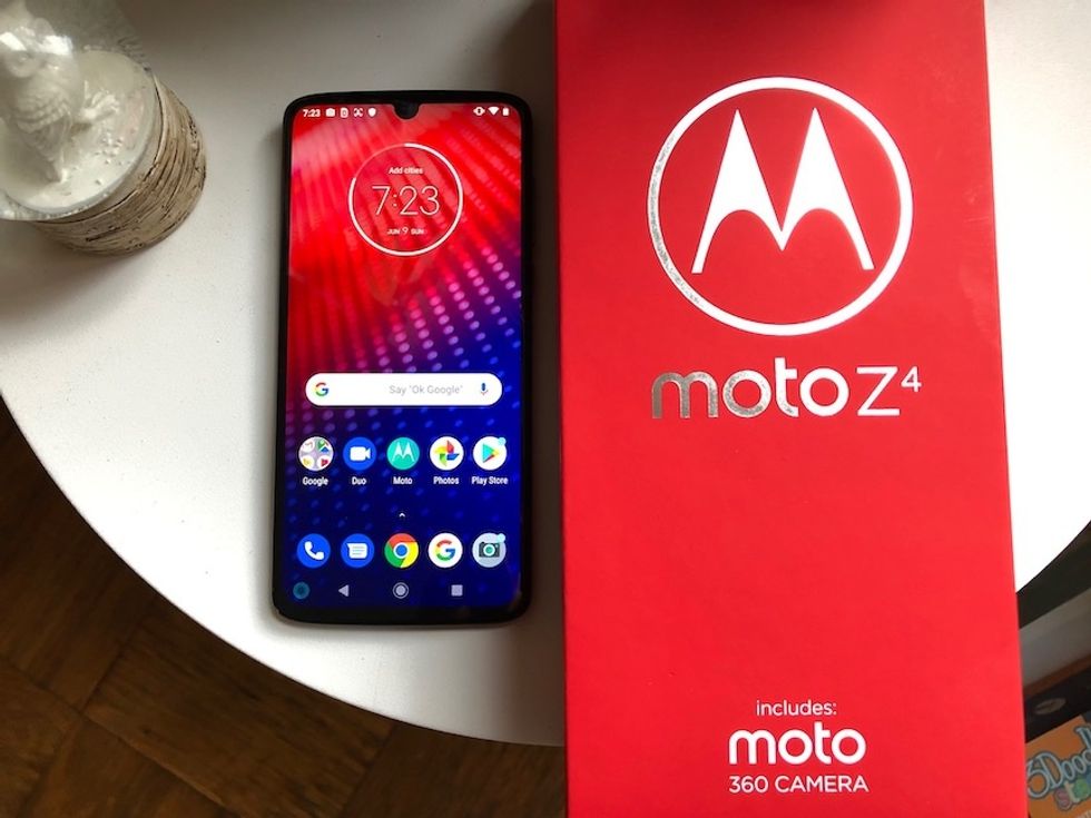 A photo of the Moto Z4 smartphone on a white plate, with the large silver M logo on the box