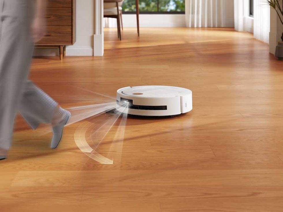 a photo of Yeedi M14 Plus avoiding a person while cleaning