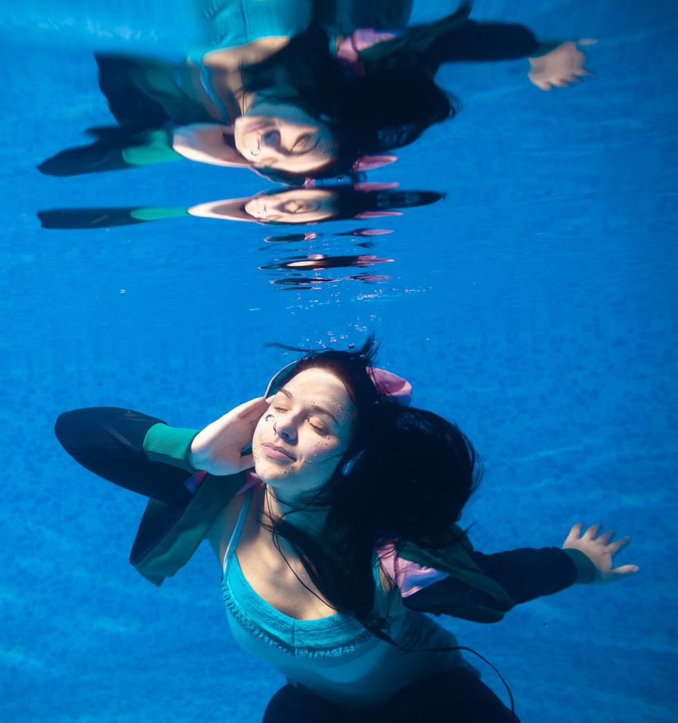 a pitcure of a woman in a pool listening to music on her headphones