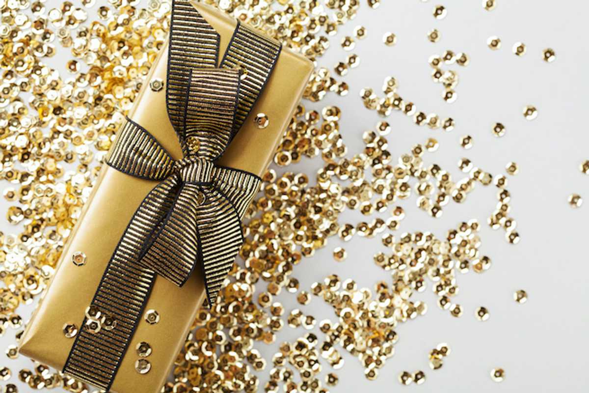 A present wrapped in gold paper with a gold ribbon, and gold sequins