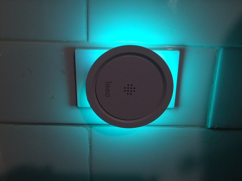 A round device, with the word "leeo" on the front with a blue light surrounding it from the back