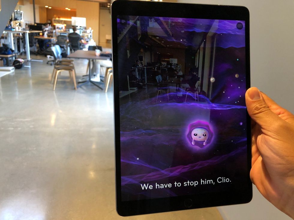 A small cartoon purple figure in a starfield on an iPad screen with words at the bottom