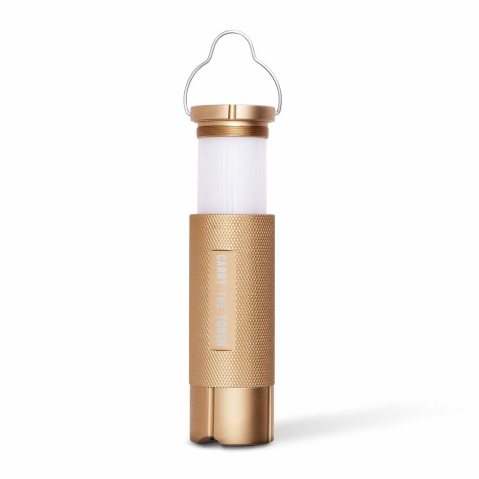 A white and gold small lamp that has a handle on top