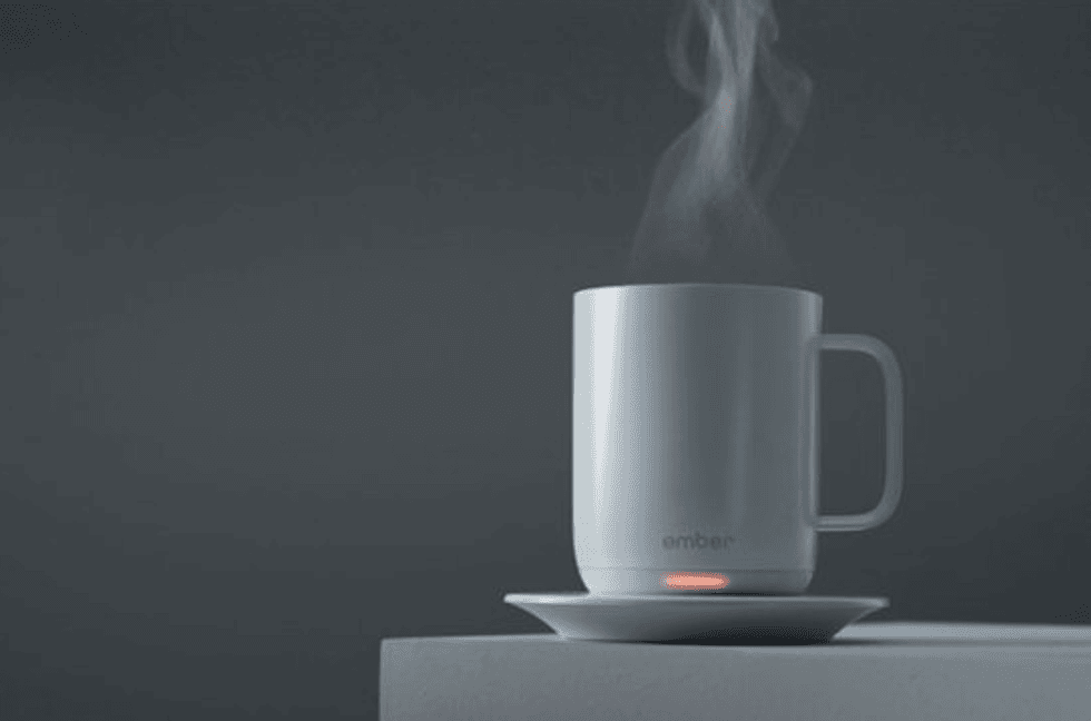 A white mug on a saucer, with a red light lit