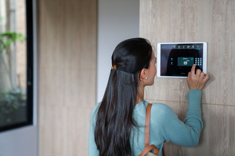 a woman entering a PIN to her smart home system