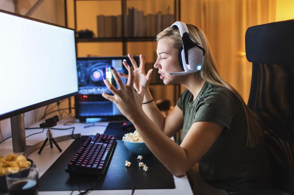a woman frustrated due to lag time sitting behind her gaming computer and setup