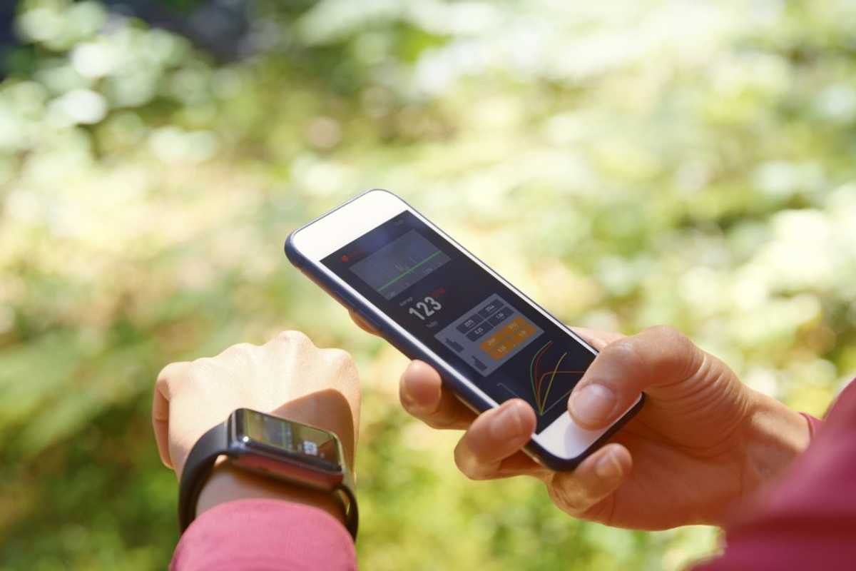 a woman syncing her smartwatch with her smartphone