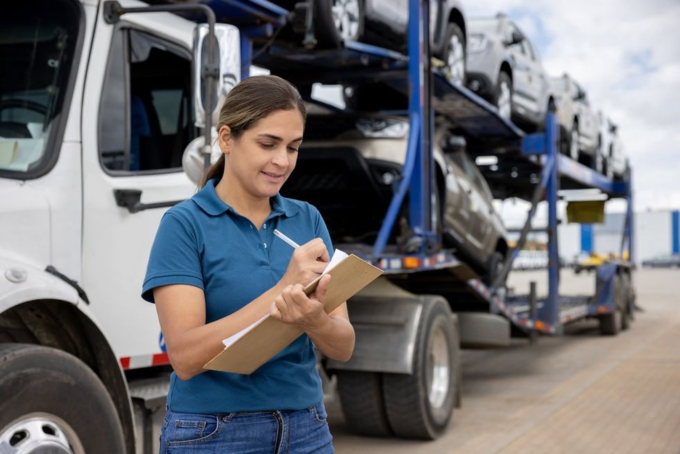 a woman writing down information about a vehicle to ship