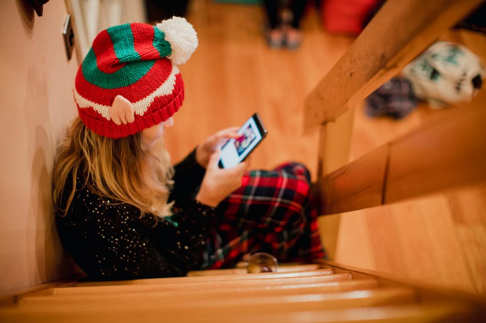 a young girl sitting on the steps on her smartphone.