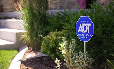 a photo of ADT sign in a garden