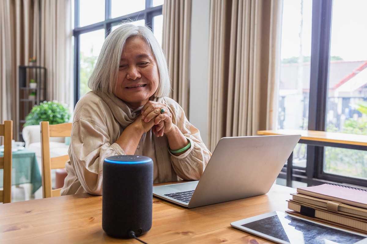 Asian senior women working with laptop computer and using smart speakers while setting in living room at home stock photo