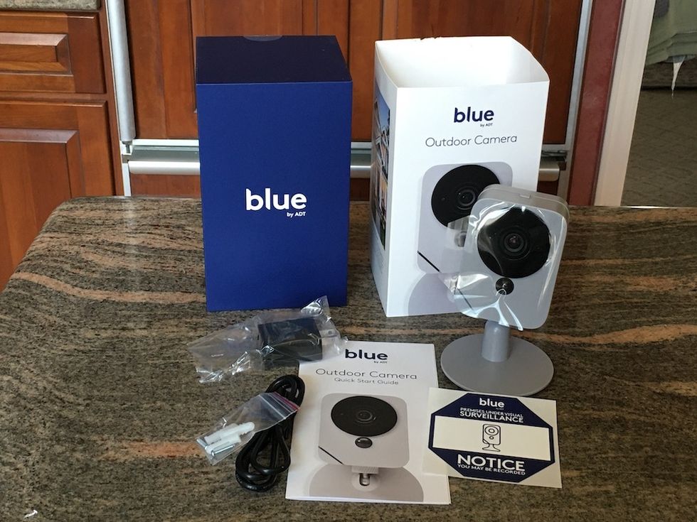Blue by ADT Outdoor Camera unboxed on a kitchen counter.