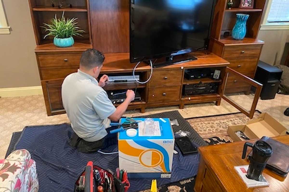 Control4 installer attaching IR reader to older consumer electronics.