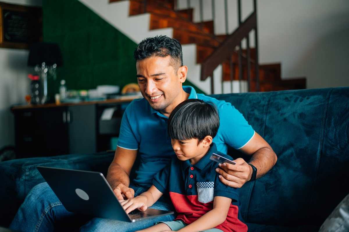 Father using the laptop with son at home stock photo