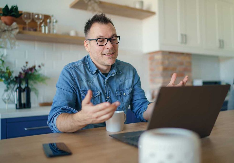 Happy adult man having a video call with a laptop at home photo
