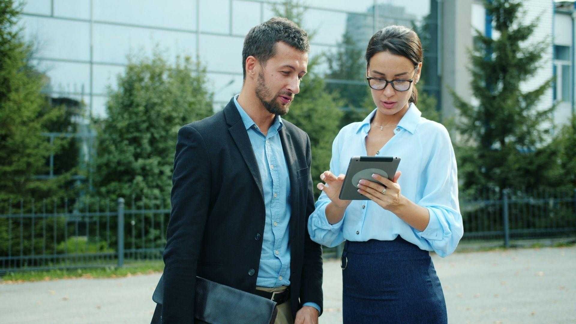 business-colleagues-discuss-work-on-tablet-outdoors