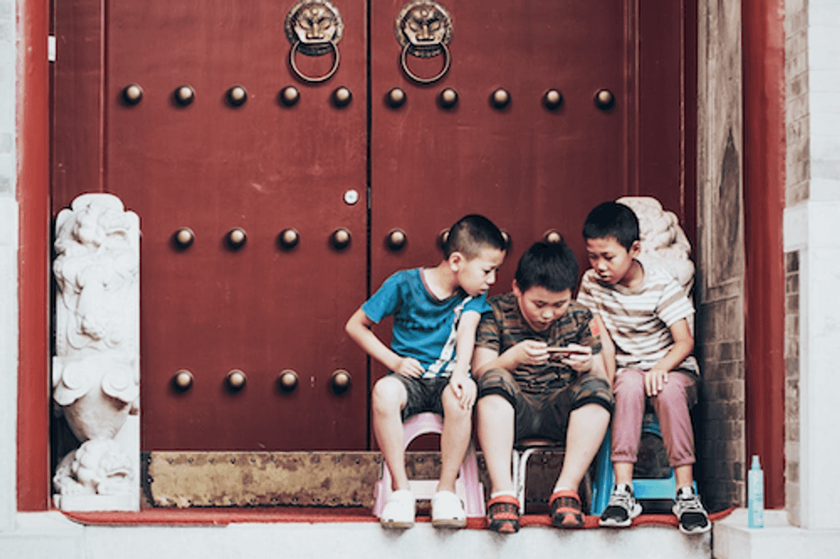 https://www.pexels.com/photo/three-boys-sitting-beside-door-2884572/hoto of kids playing PUBG UC game on a mobile device.