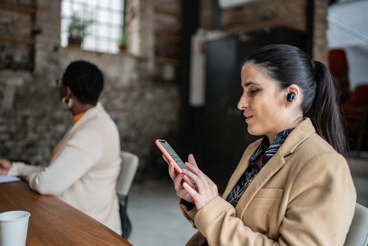 a woman wearing wireless earbuds on her smartphone