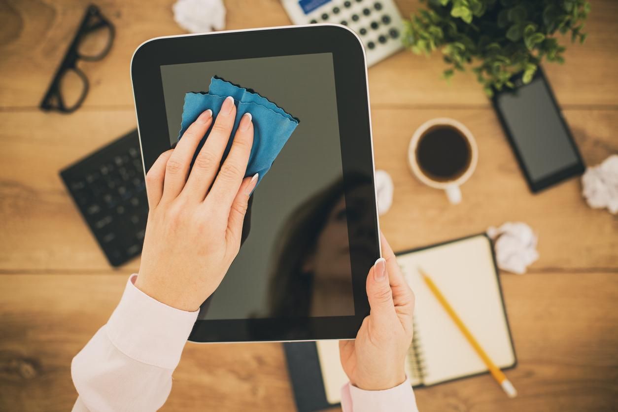 a person wiping a tablet's screen with a cloth