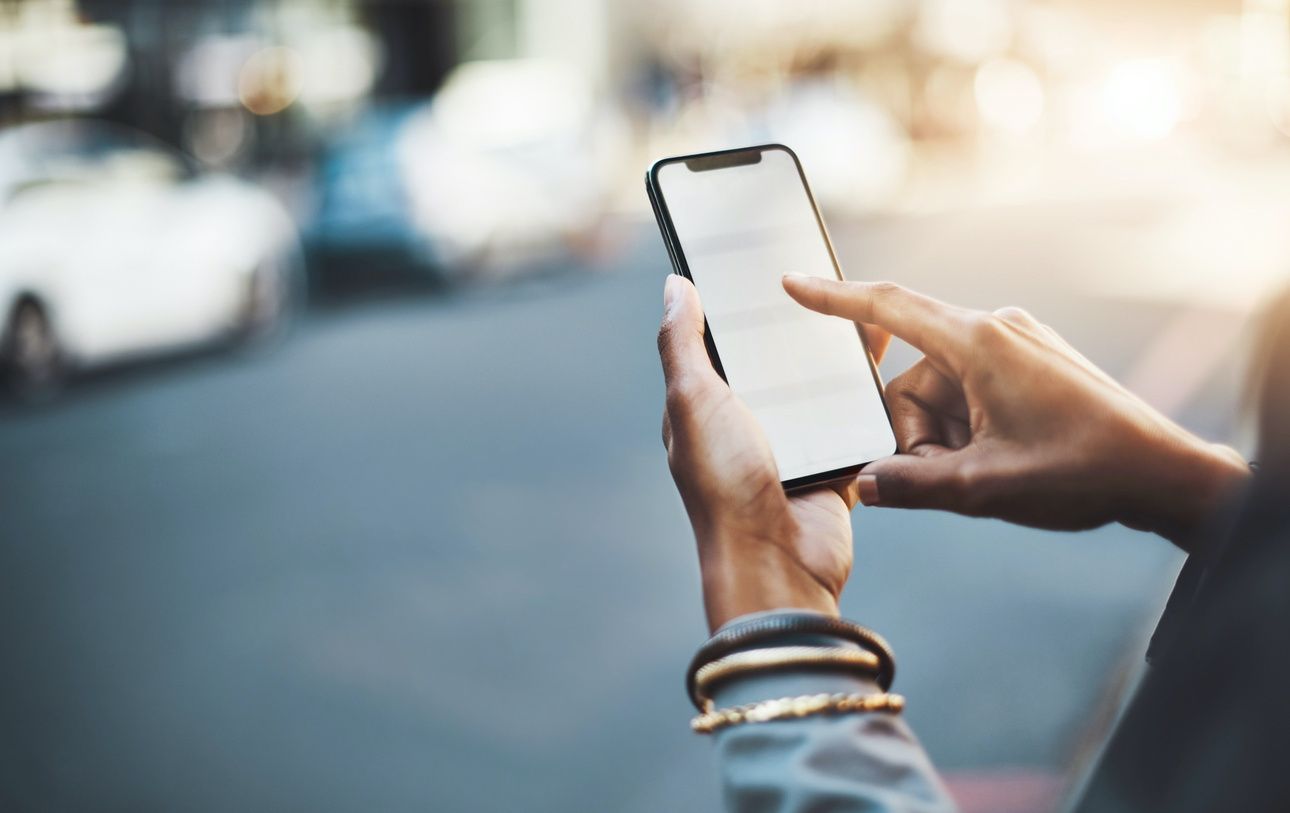 Someone holding an iPhone in their hands while standing on the street