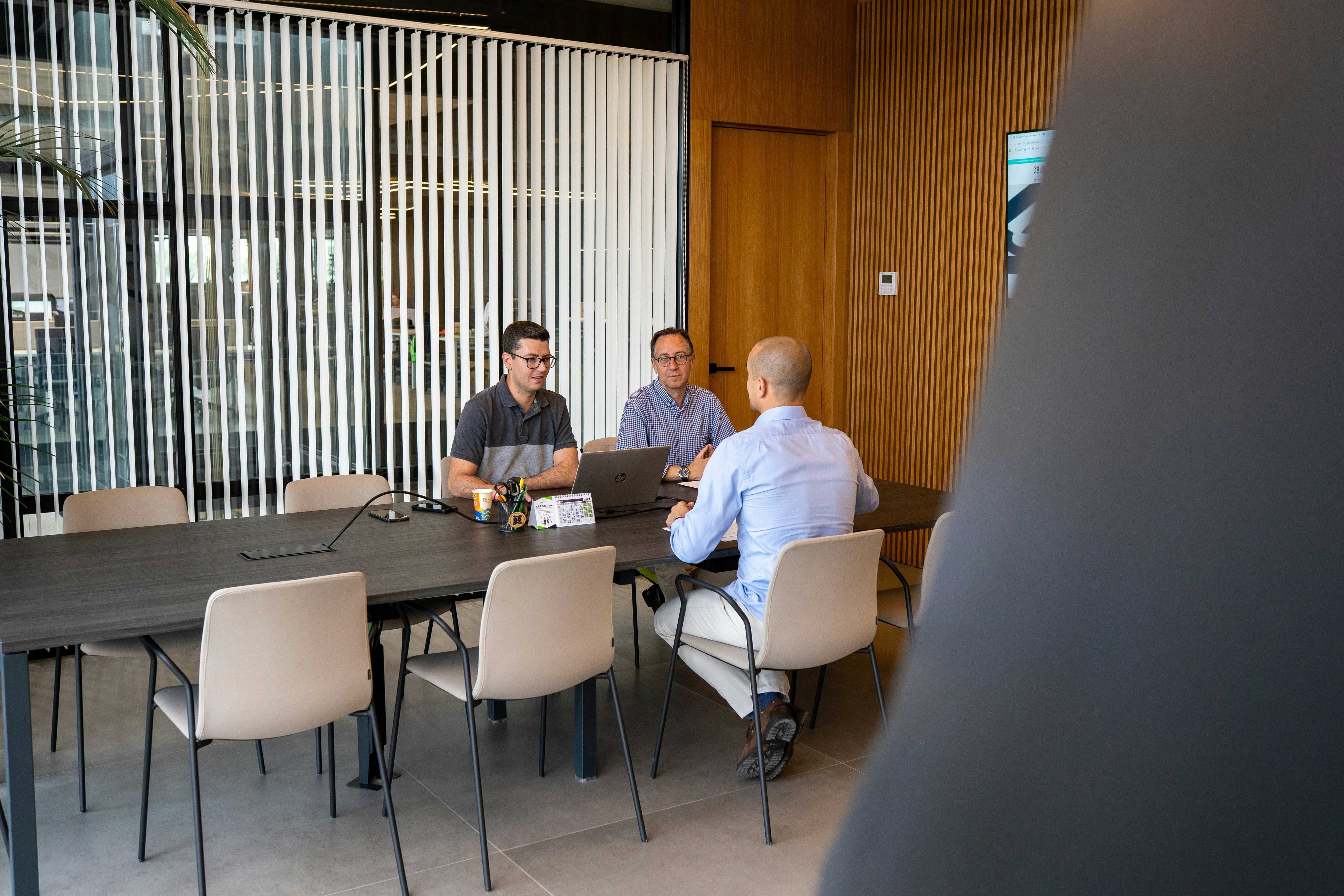 Three men in a meeting at a long table in a modern office
