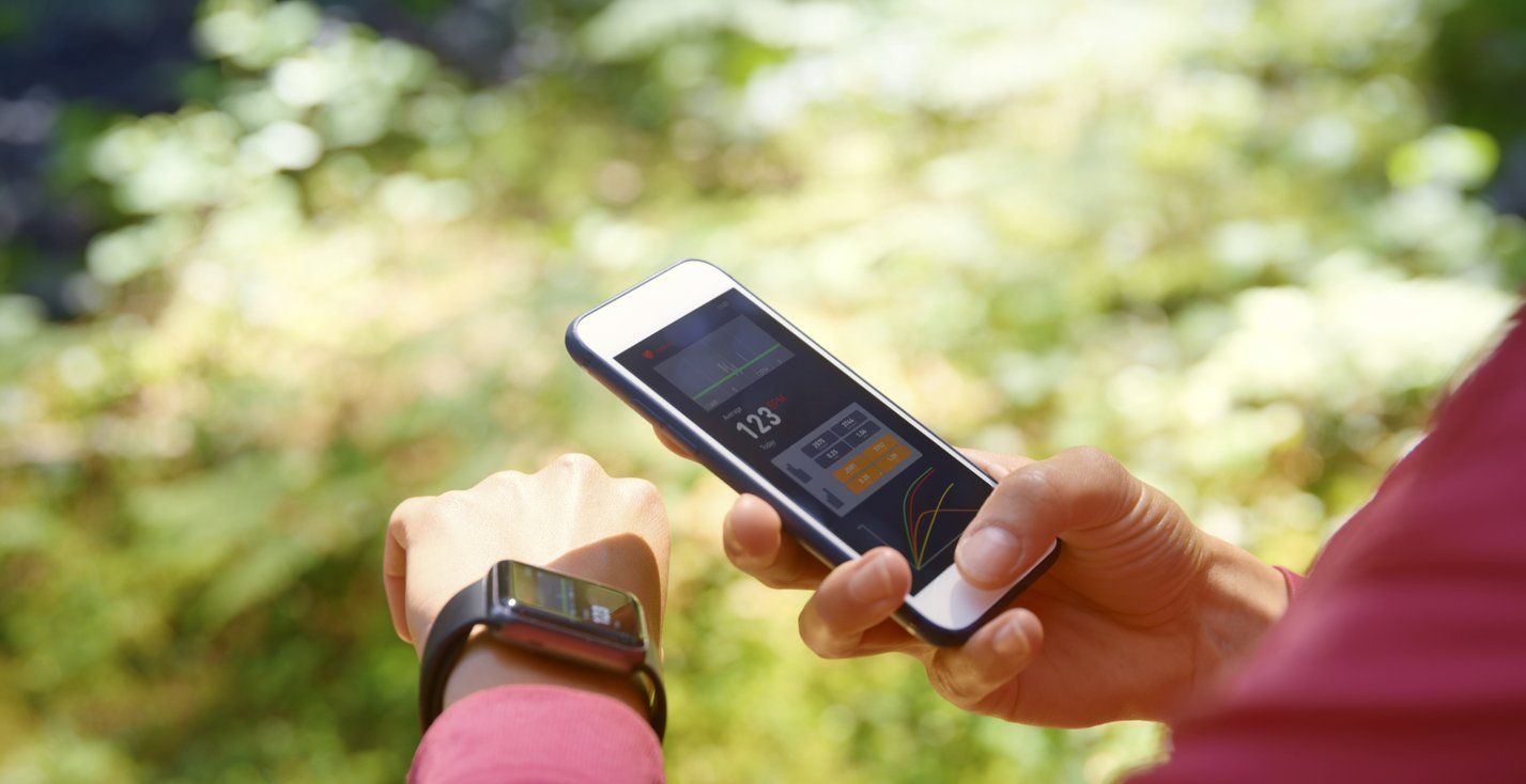 a woman syncing her smartwatch with her smartphone