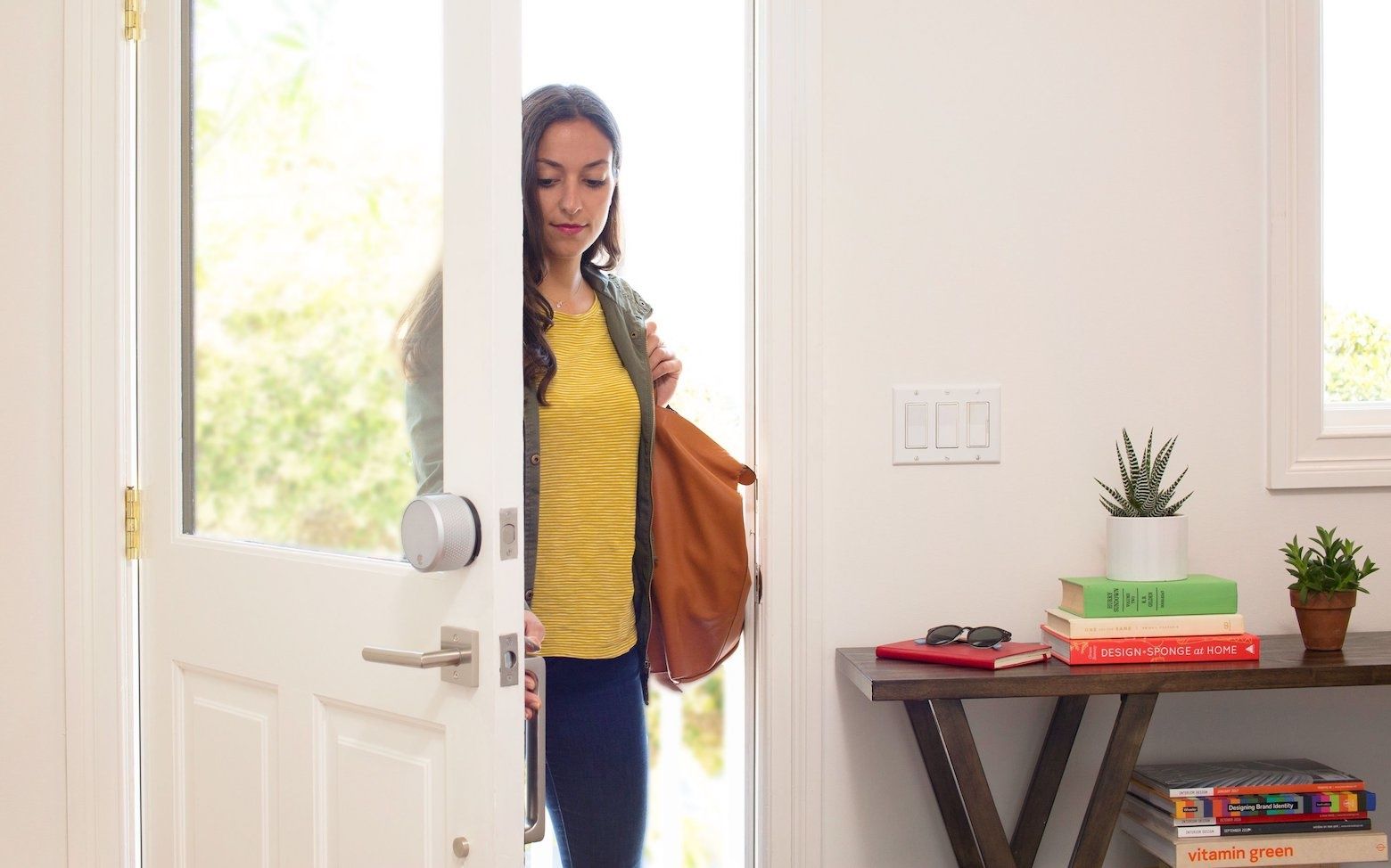 A woman walking into a home with a Yale smart lock on the door