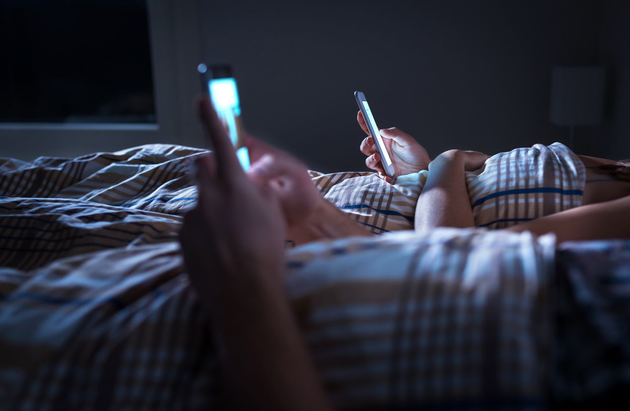 Couple using smartphones in bed