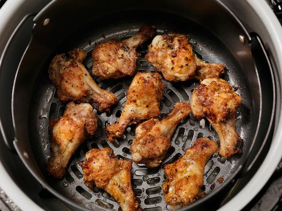 An air fryer with chicken wings cooked inside