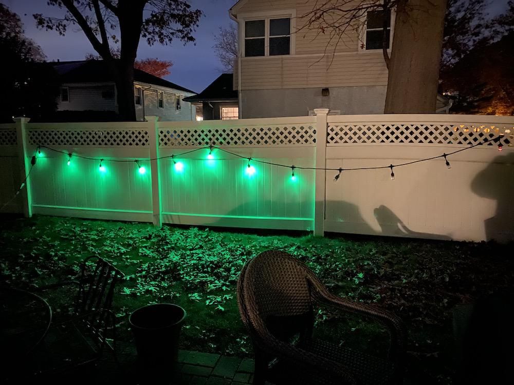 Enbrighten LED Wi-Fi Smart Cafe Lights installed on a fence outside.