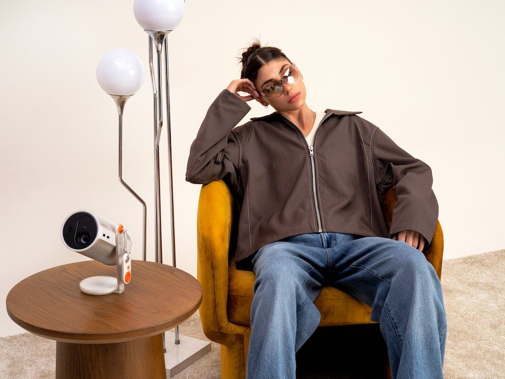 photo of a woman sitting in a chair with Xgimi MoGo 4 portable projector on a table.