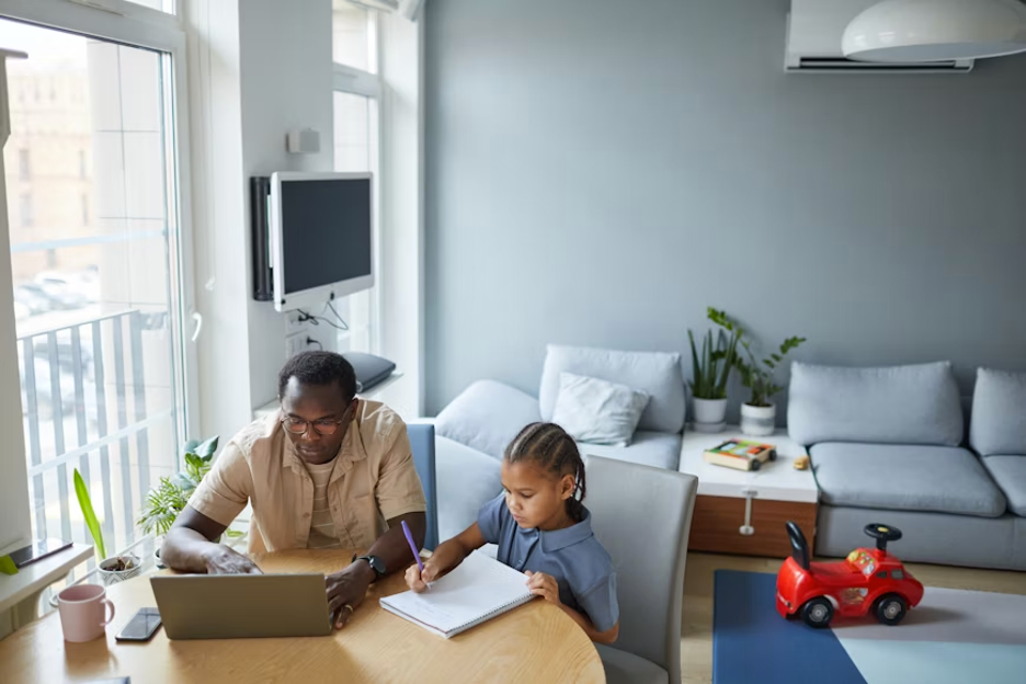 a photo of a father and son doing homework at a table in a home.