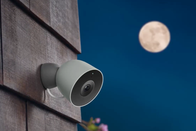 photo of Google Nest Cam 2nd Gen on a home at night with moon showing in the sky.