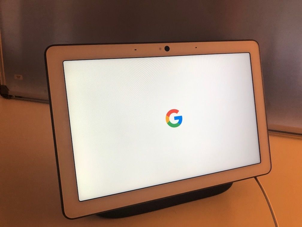 The Google Home Max with the Google logo on the screen on a white cabinet