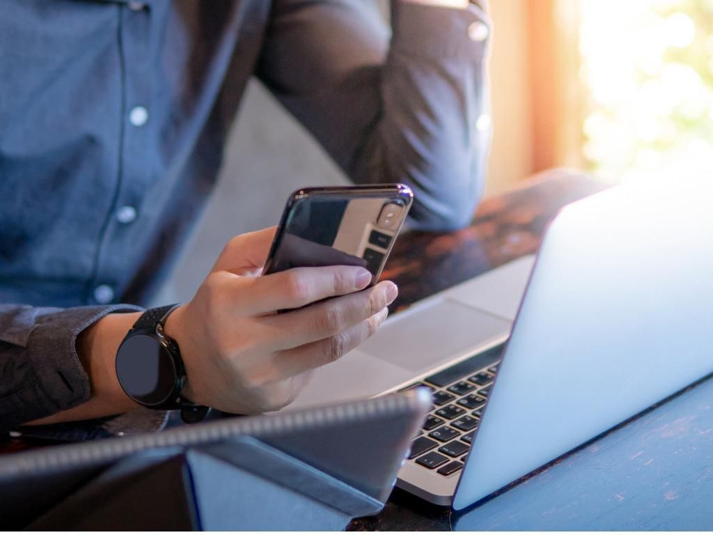 Man holding a smartphone over a computer