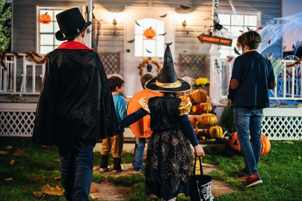 Trick or treaters going to a front door on Halloween night.