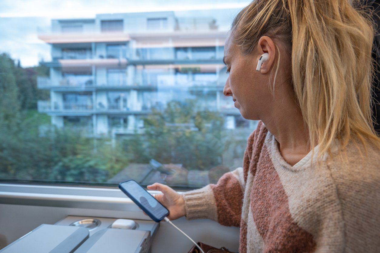 a woman wearing earbuds and on her cellphone on a train.