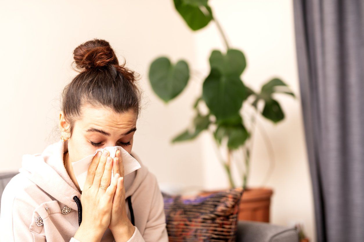 a woman sneezing inside her home.