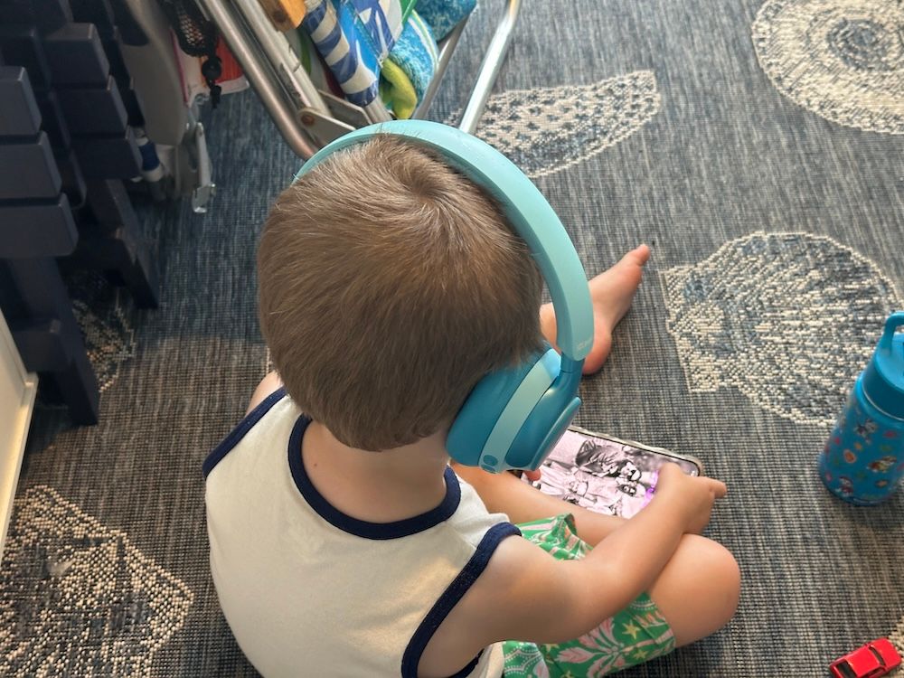 photo of a boy wearing iClever Q950 headphones while watching video on a smartphone