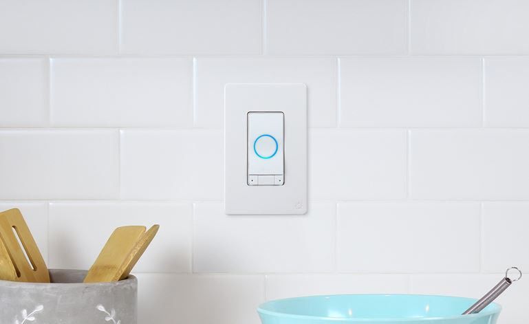 A white wall switch with a blue light circle in the middle on a white, tiled wall