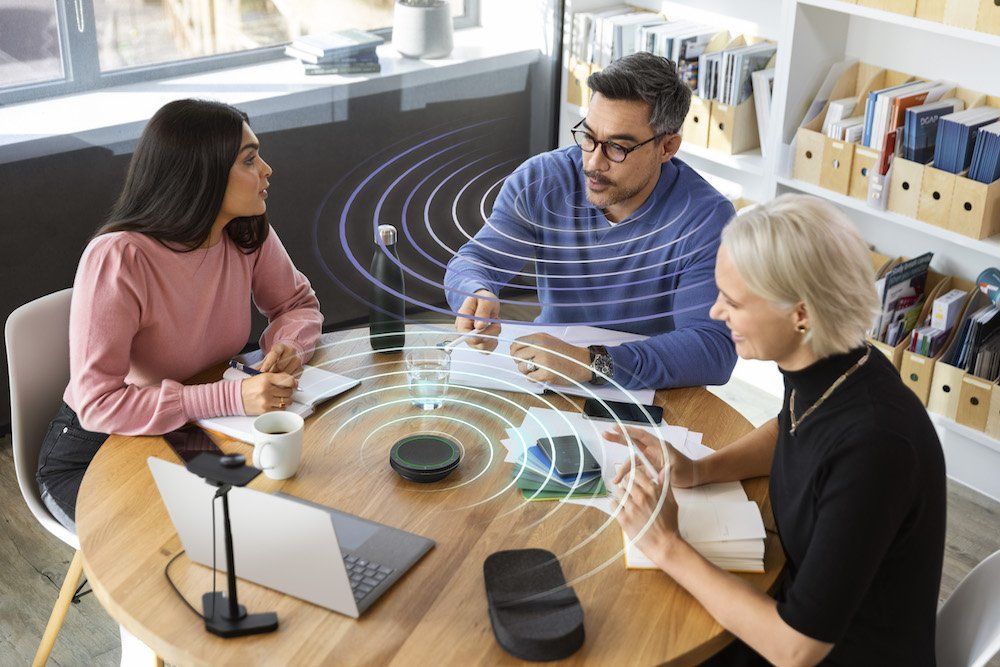 a photo of three people on a conference call with a Jabra speakerphone Speak2 75