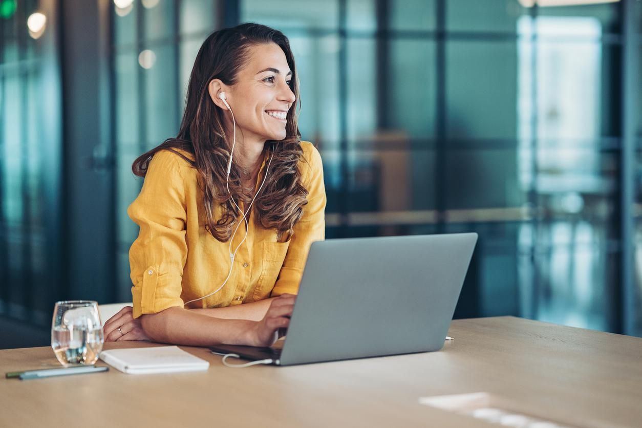 A photo of a woman wearing headphones and working on a computer