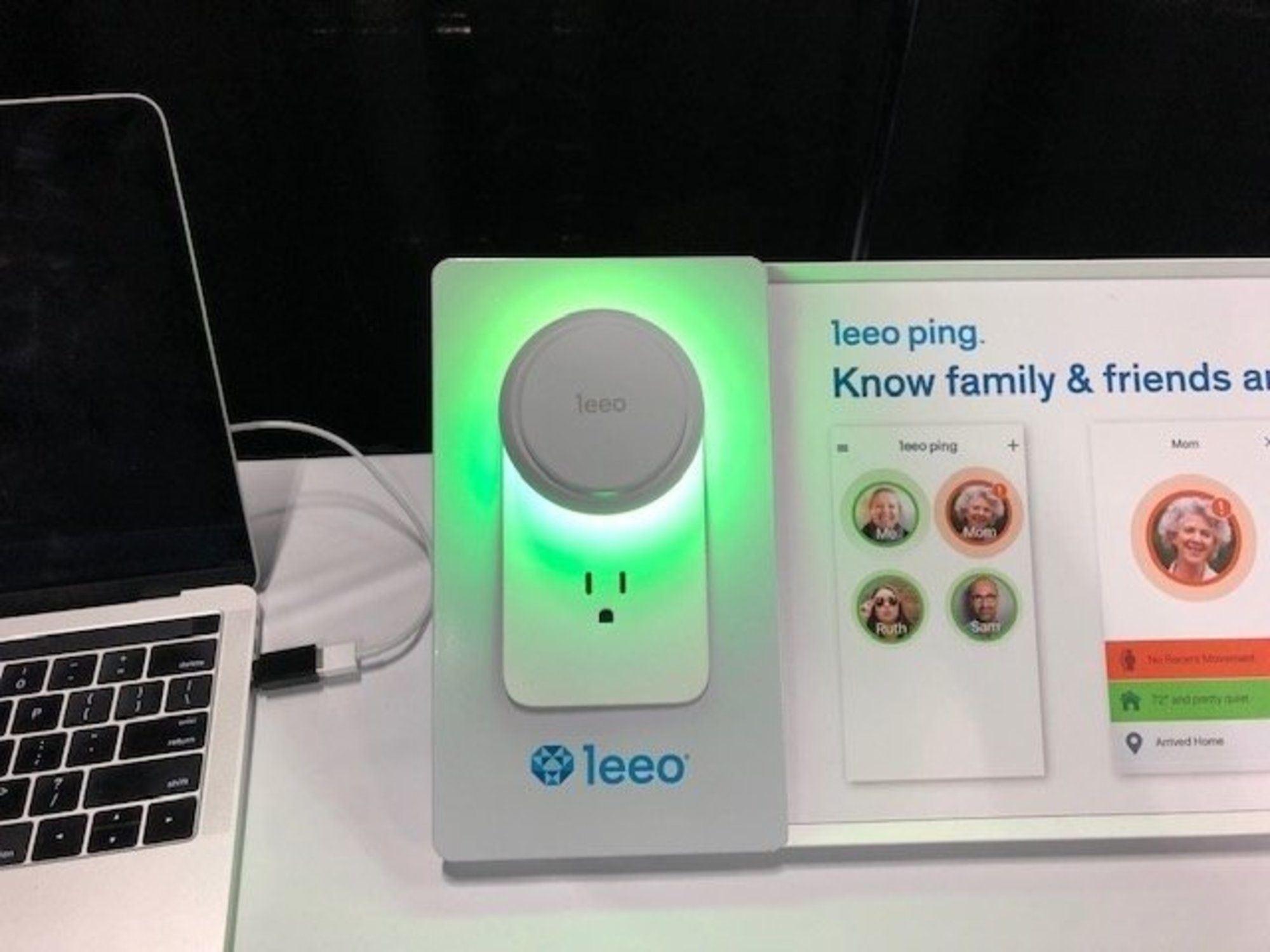 A smart device glowing green on a white table, with the name ‘leeo’