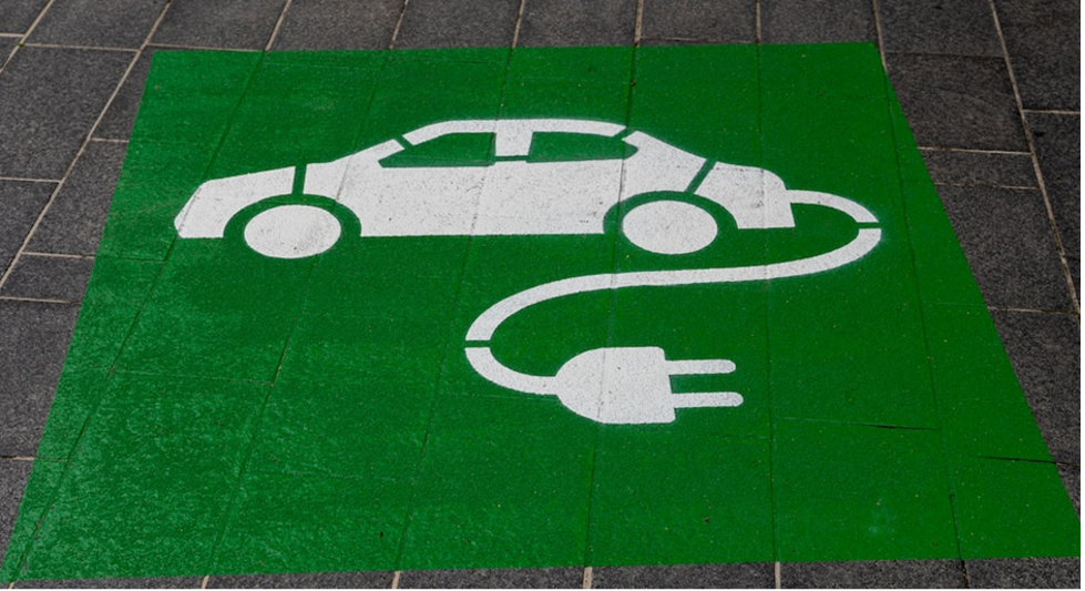 an imagre of a doormat with an illustration of an electric car and power cord.