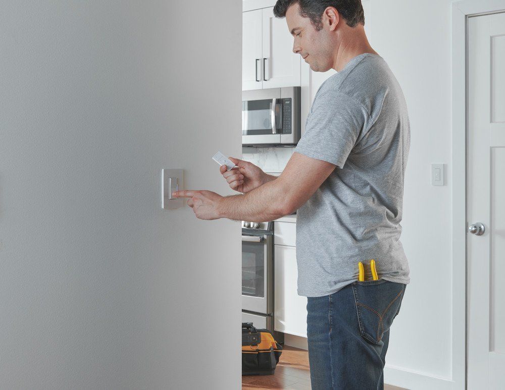 a photo of a man installing Lutron Caseta Dimmer Switch
