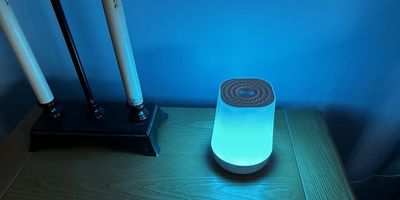 a photo of Momcozy Smart Baby Sound Machine on a nightstand with rainbow colors showing