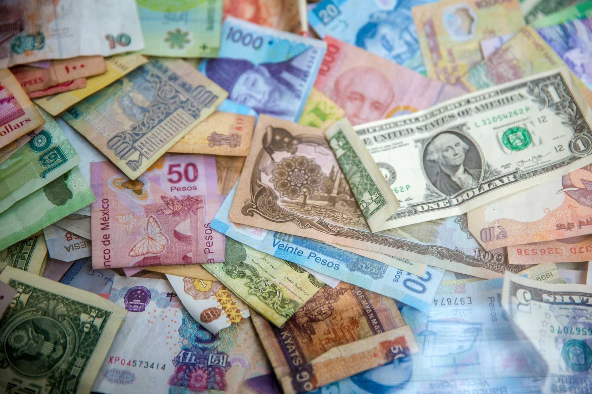 A collection of various international banknotes scattered across a flat surface