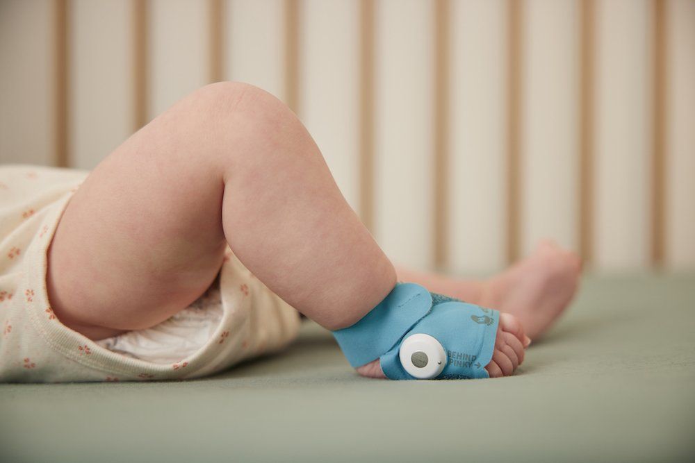 a photo of a baby wearing Owlet BabySat in a crib