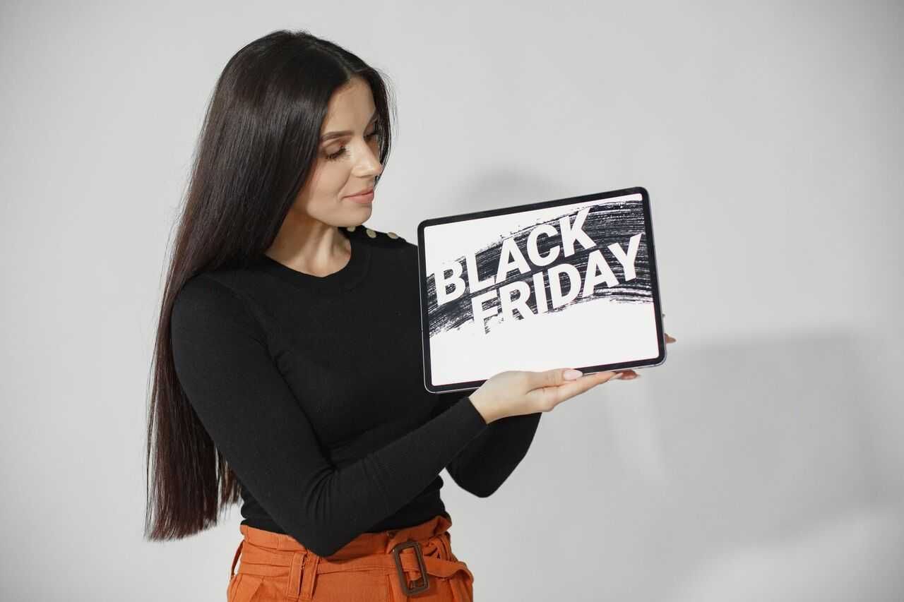 a photo of a woman holding up a tablet that reads Black Friday